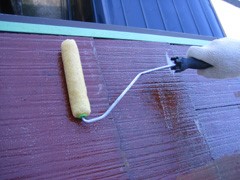屋根にローラーで下塗り材を塗る